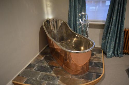 a copper tub in a bathroom with a shower at Long Melford Swan in Long Melford