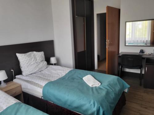 1 dormitorio con 1 cama con manta verde y escritorio en Selment Resort, en Ełk