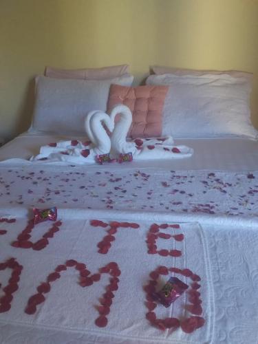 a bed with a white bedspread with red flowers on it at Pousada Canto Feliz in Serra do Cipo
