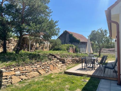 a patio with a table and chairs and a stone wall at Domek v Podyjí in Lukov
