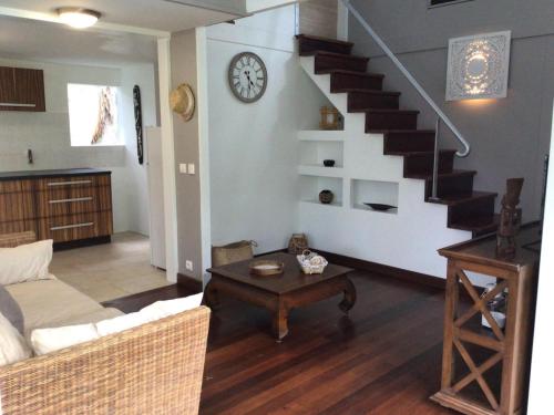 ein Wohnzimmer mit einer Treppe und einem Tisch in der Unterkunft Le Cottage in Sainte-Rose