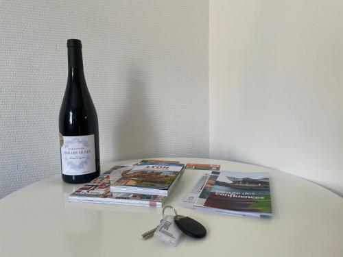 uma garrafa de vinho sentada numa mesa ao lado de uma revista em Time Capsule - Studio cosy em Caluire-et-Cuire