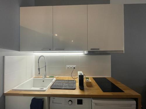 a kitchen with white cabinets and a sink and a keyboard at Time Capsule - Studio cosy in Caluire-et-Cuire
