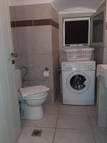 a small bathroom with a washing machine and a tv at Vila kavalina Leukada Kavalos in Asprogerakata