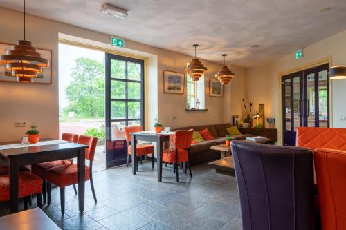 a restaurant with tables and chairs and a couch at Lentemaheerd in Uithuizermeeden