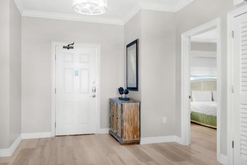 a white bedroom with a door and a bed at Hidden Dunes 304 in Panama City Beach