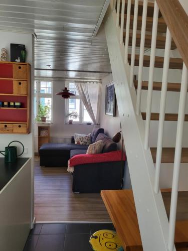 a living room with a couch and a staircase at Det lille hus in Middelfart