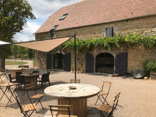 a patio with tables and chairs and an umbrella at Ratatouille in Mayrinhac-Lentour