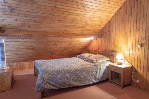 1 dormitorio con 1 cama y pared de madera en Domaine de karoli, en Barneville-sur-Seine