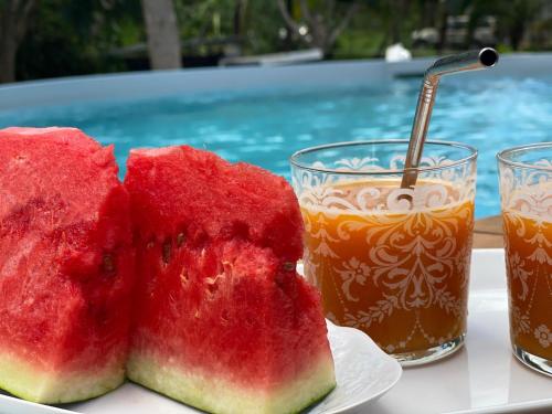 two slices of watermelon on a plate next to two drinks at Locastudio - Grenadine in Sainte-Anne