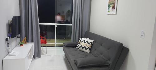 un salon avec un canapé noir et une télévision dans l'établissement Flat Bem-vindo Bella Maré, à Maragogi
