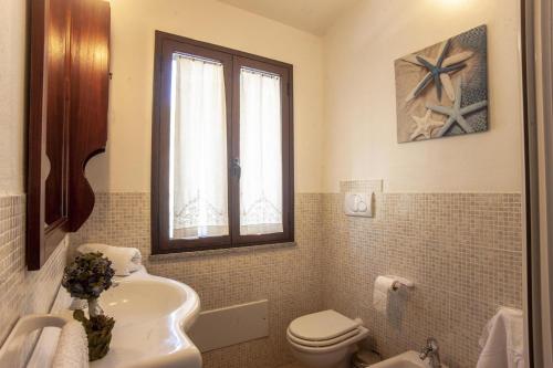 a bathroom with a sink toilet and a window at Villa Litoranea Santa Margherita di Pula in Domus de Maria