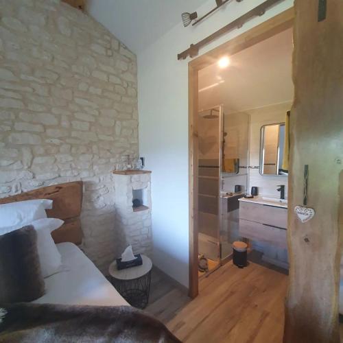 a bedroom with a bed and a stone wall at La babounette in Jaujac