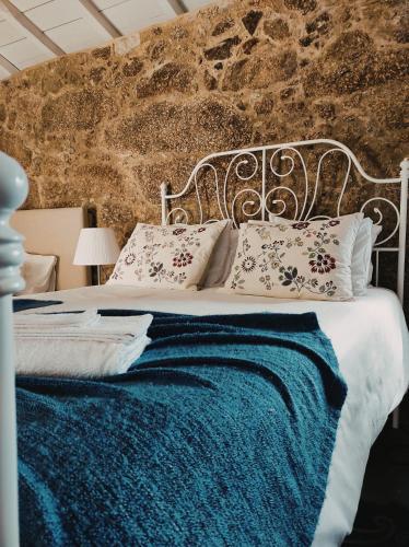 a bed with a blue blanket and pillows on it at Casas da Quinta da Cancela in Balugães