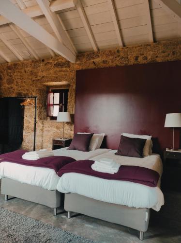 two beds in a bedroom with a red wall at Casas da Quinta da Cancela in Balugães