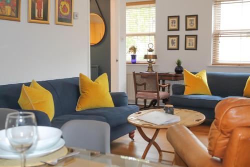 a living room with blue couches and yellow pillows at Sydney Wharf House in Bath