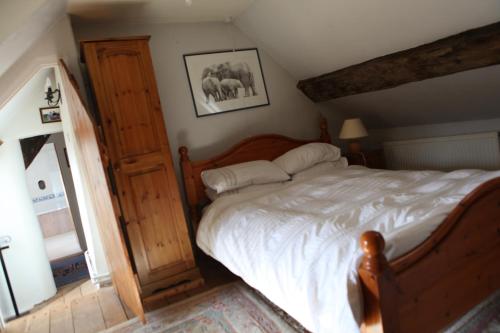 een slaapkamer met een groot bed met een houten frame bij Medieval Cottage in rural Monmouthshire. in Raglan