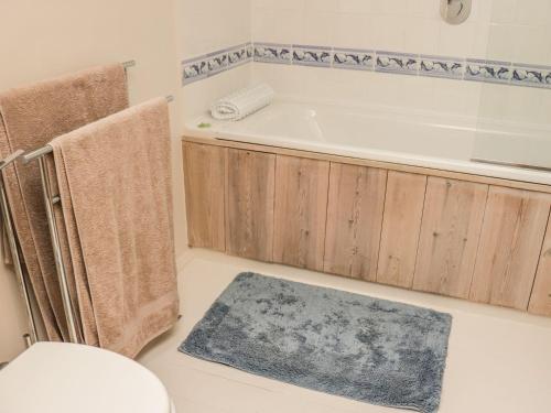 y baño con bañera, aseo y alfombra. en Medieval Cottage in rural Monmouthshire. en Raglan