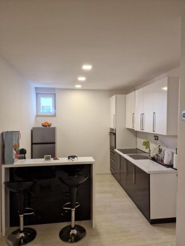 Široki BrijegにあるWellness apartment BLACK-WHITEの白いキャビネットとバースツール付きの黒い島のあるキッチンが備わります。