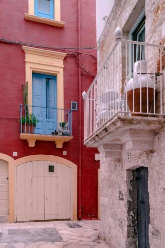 a red building with white doors and a balcony at Quattro Perle in Polignano a Mare