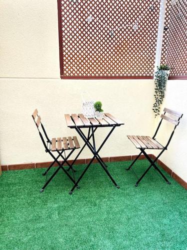 une table et deux chaises assises à côté d'un mur dans l'établissement Precioso apartamento, à Malaga