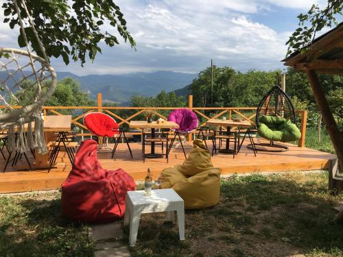 a wooden deck with tables and chairs with mountains in the background at Berkri Gastro Yard & Guest House in Yenokavan