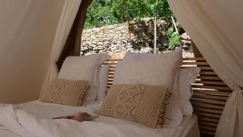 1 dormitorio con cama con almohadas y ventana en Amaraxe Ecoglamping, en Miñortos
