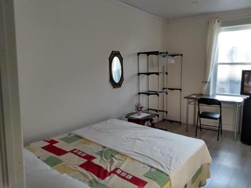 Schlafzimmer mit einem Bett, einem Schreibtisch und einem Fenster in der Unterkunft Healing Touch Holistic Living Space in Amherst