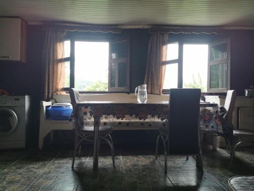 Una cocina con mesa y sillas y dos ventanas. en Guest House Eceri, en Mestia
