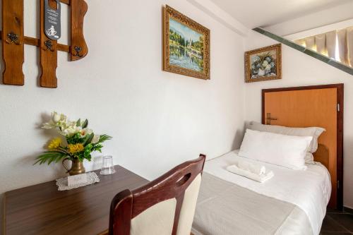 a bedroom with a bed and a table with a vase of flowers at Jagodic Garni Hotel in Cerklje na Gorenjskem