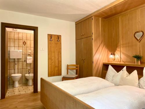 a bedroom with a bed and a bathroom with a toilet at Chalet Forciagn in San Vigilio Di Marebbe