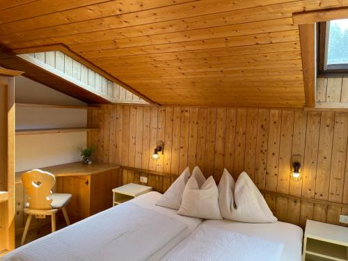 a bedroom with a white bed in a wooden room at Chalet Forciagn in San Vigilio Di Marebbe