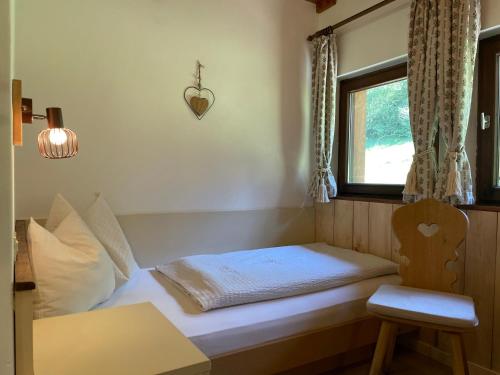 a bed in a room with a window and a chair at Chalet Forciagn in San Vigilio Di Marebbe