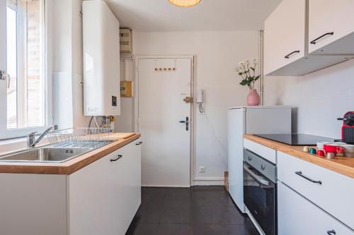 La cuisine blanche est équipée d'un évier et d'un réfrigérateur. dans l'établissement Le Majorelle - 2 chambres - Centre Gare, à Reims