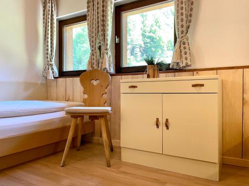 a bedroom with a bed and a chair and a window at Chalet Forciagn in San Vigilio Di Marebbe