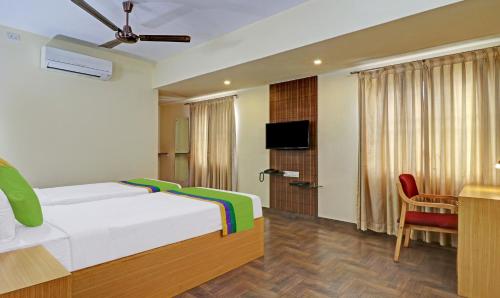 a bedroom with a bed and a desk and a television at Treebo Akshaya Mayflower Vijaya Bank Layout in Bengaluru