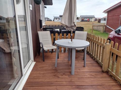 a table and chairs on a balcony with an umbrella at D&D Holiday Chalet in Bridlington