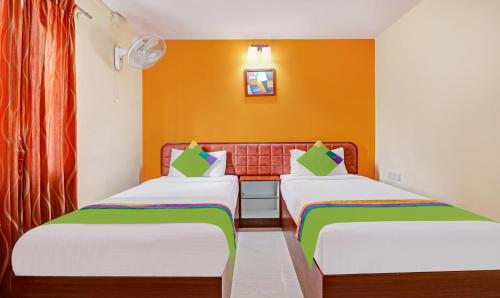 two beds in a room with orange walls at Treebo Akshaya Mayflower Vijaya Bank Layout in Bengaluru