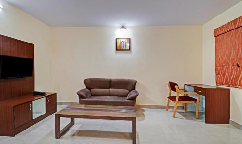 a living room with a chair and a tv at Treebo Akshaya Mayflower Vijaya Bank Layout in Bengaluru