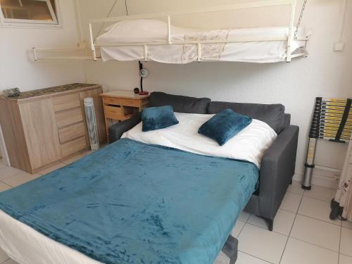 a bed with two blue pillows on top of it at Ground floor studio with access to beach and pool in Le Barcarès