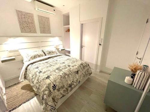 a white bedroom with a bed and a table at Beach House Old Town in Cascais