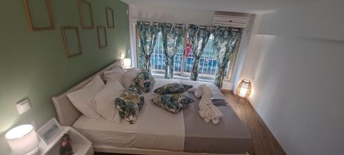 um quarto com uma cama com almofadas e uma janela em The Owl nest Modern and Cozy place in the Historical Center em Atenas