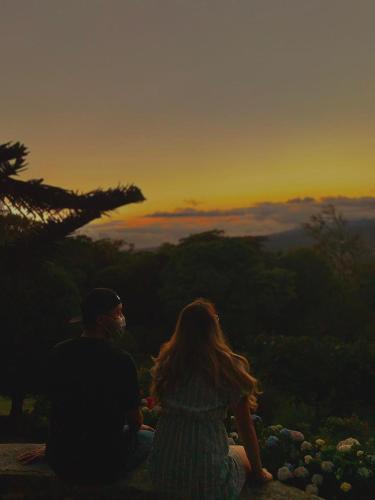 a man and woman sitting on a rock watching the sunset at Cabañas El Parador in Boquete