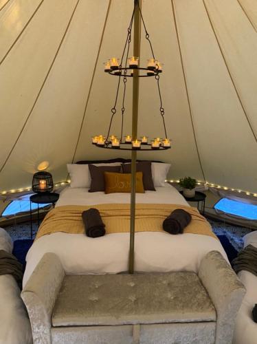 - une chambre avec un grand lit dans une tente dans l'établissement Eakley Manor Farm Glamping, à Newport Pagnell