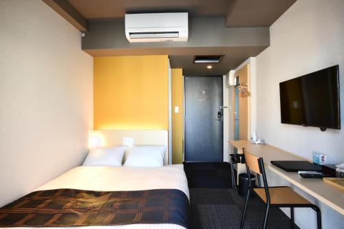 um quarto de hotel com uma cama e uma televisão de ecrã plano em FL Hotel Asakusa em Tóquio