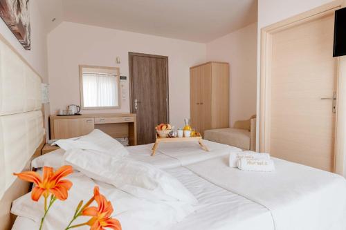 a large white bed in a room with orange flowers at Vournelis Beach Hotel and Spa in Iraklitsa