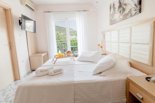 two white beds in a room with a window at Vournelis Beach Hotel and Spa in Iraklitsa