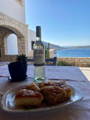 a plate of food and a bottle of wine on a table at Stonehouse villas with breathtaking view in Sitia