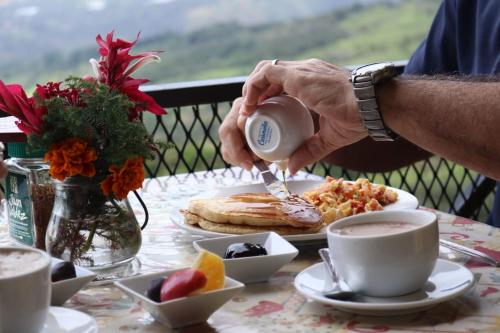 un hombre está vertiendo café en un plato de comida en Cabañas El Parador en Boquete