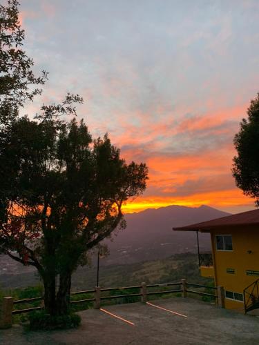 a sunset with a tree in front of a building at Cabañas El Parador in Boquete